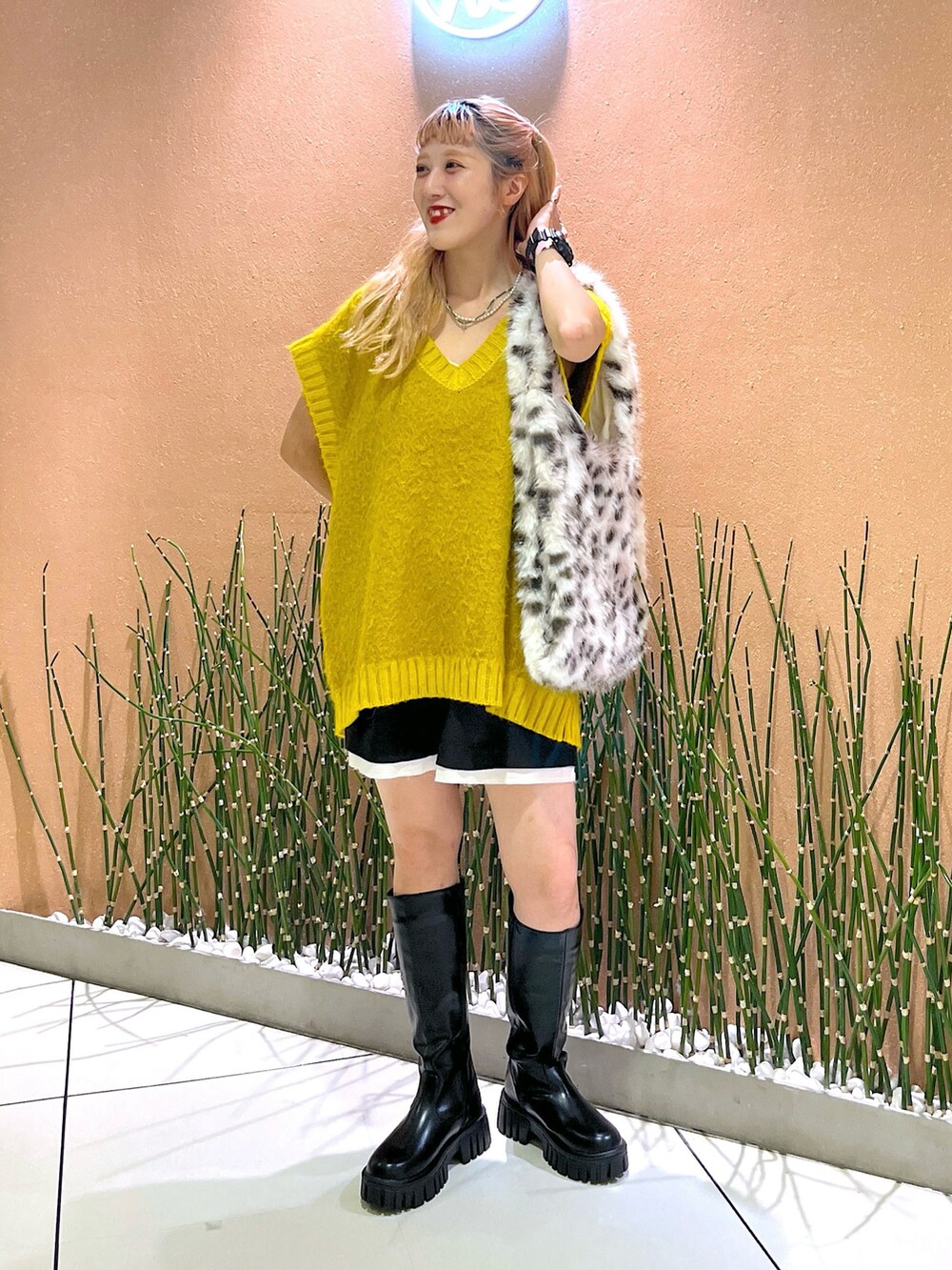 イエロー系のベスト、ブラック系のブーツを着用したレディースの秋コーディネートの2枚目の写真