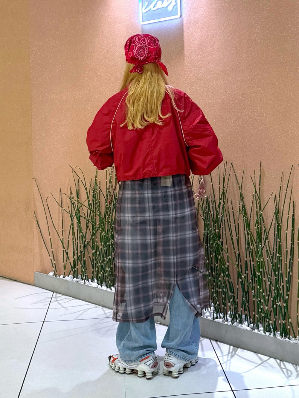 レッド系のブルゾン、ベージュ系のスカート、ブルー系のデニムパンツを着用したレディースの夏コーディネートの2枚目の写真