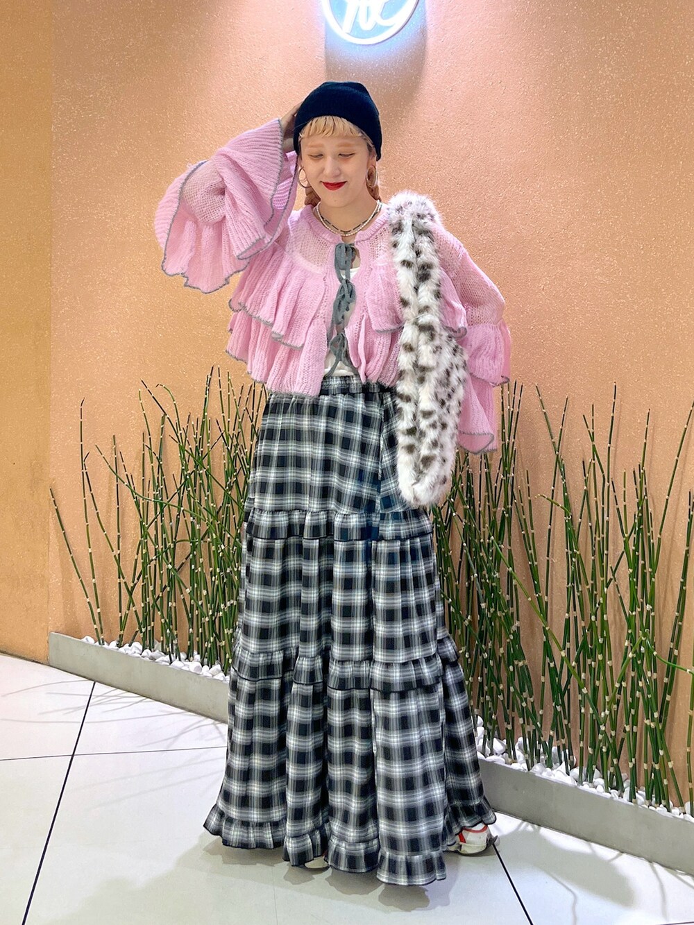 ブラック系のスカート、ピンク系のニット/セーター、ホワイト系のスニーカーを着用したレディースの秋コーディネートの2枚目の写真