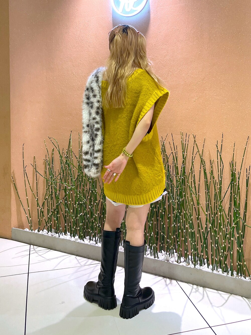 イエロー系のベスト、ブラック系のブーツを着用したレディースの秋コーディネートの3枚目の写真