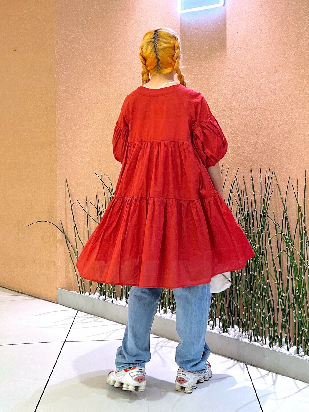 レッド系のワンピース/ドレス、ブラック系のデニムパンツ、ホワイト系のスニーカーを着用したレディースの夏コーディネートの3枚目の写真