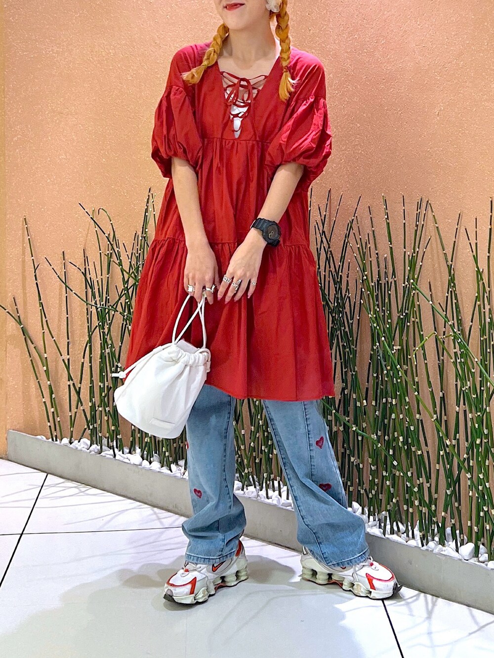 レッド系のワンピース/ドレス、ブラック系のデニムパンツ、ホワイト系のスニーカーを着用したレディースの夏コーディネートの4枚目の写真