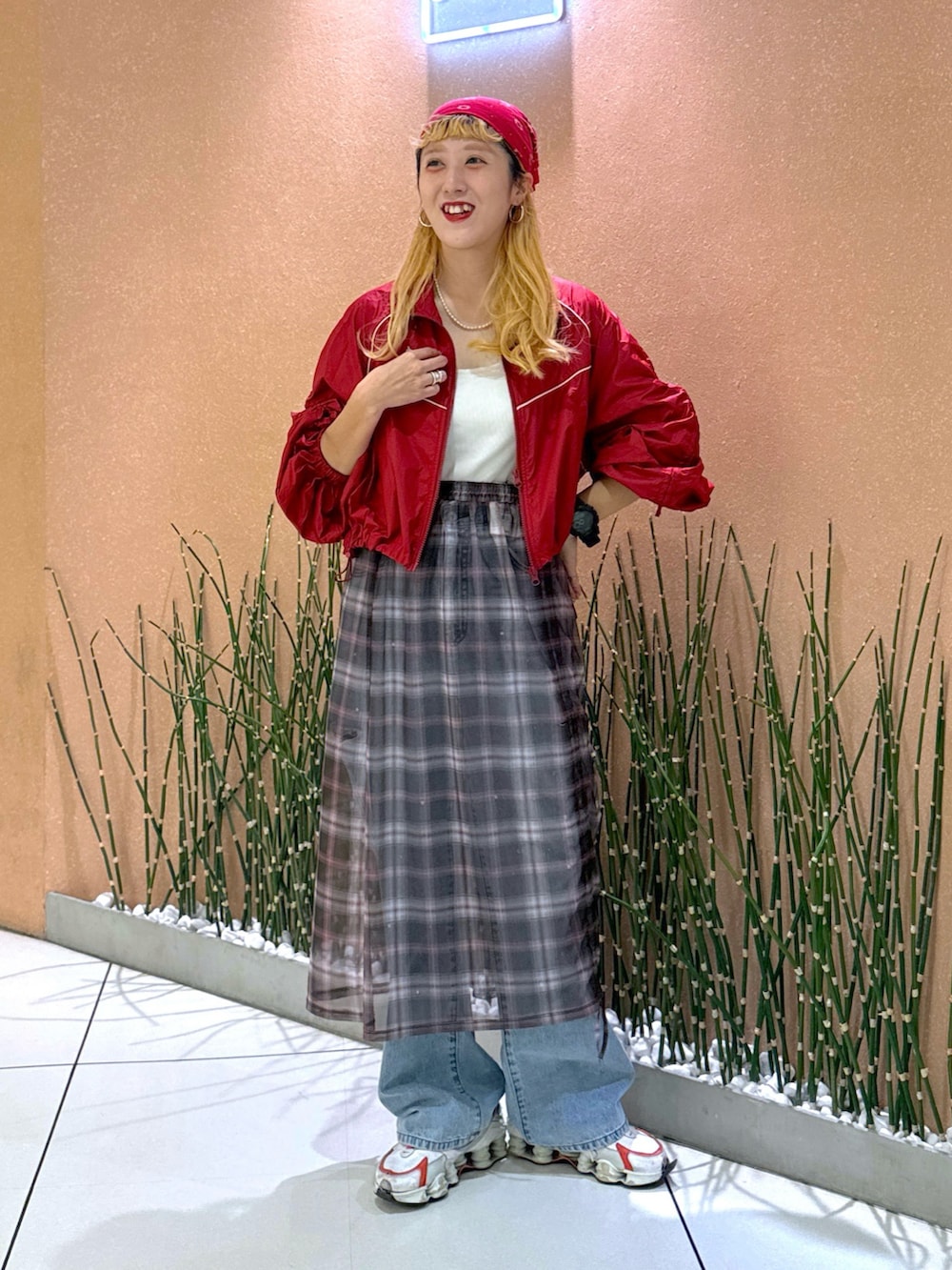 レッド系のブルゾン、ベージュ系のスカート、ブルー系のデニムパンツを着用したレディースの夏コーディネートの3枚目の写真