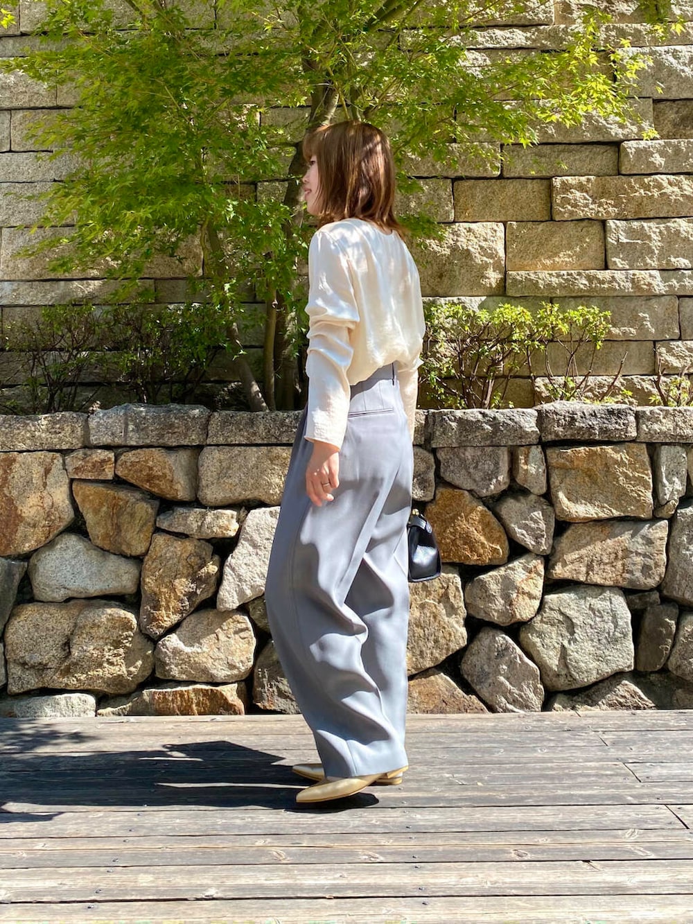 ブラック系のハンドバッグ、ゴールド系のパンプス、グレー系のその他パンツを着用したレディースの夏コーディネートの6枚目の写真