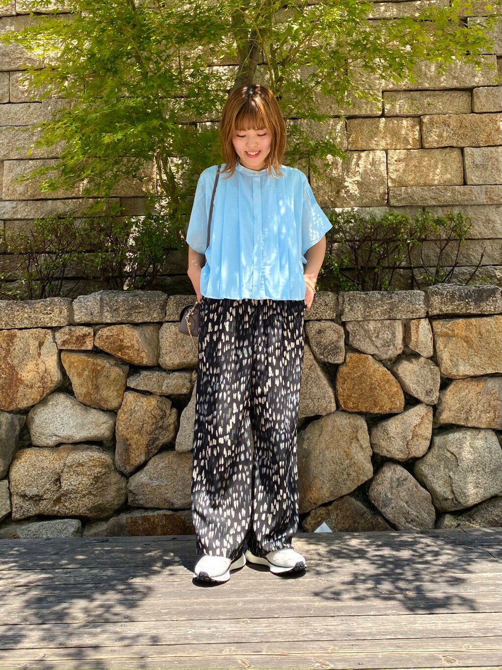 グレー系のショルダーバッグ、ホワイト系のスニーカー、ブルー系のシャツ/ブラウスを着用したレディースの夏コーディネートの2枚目の写真