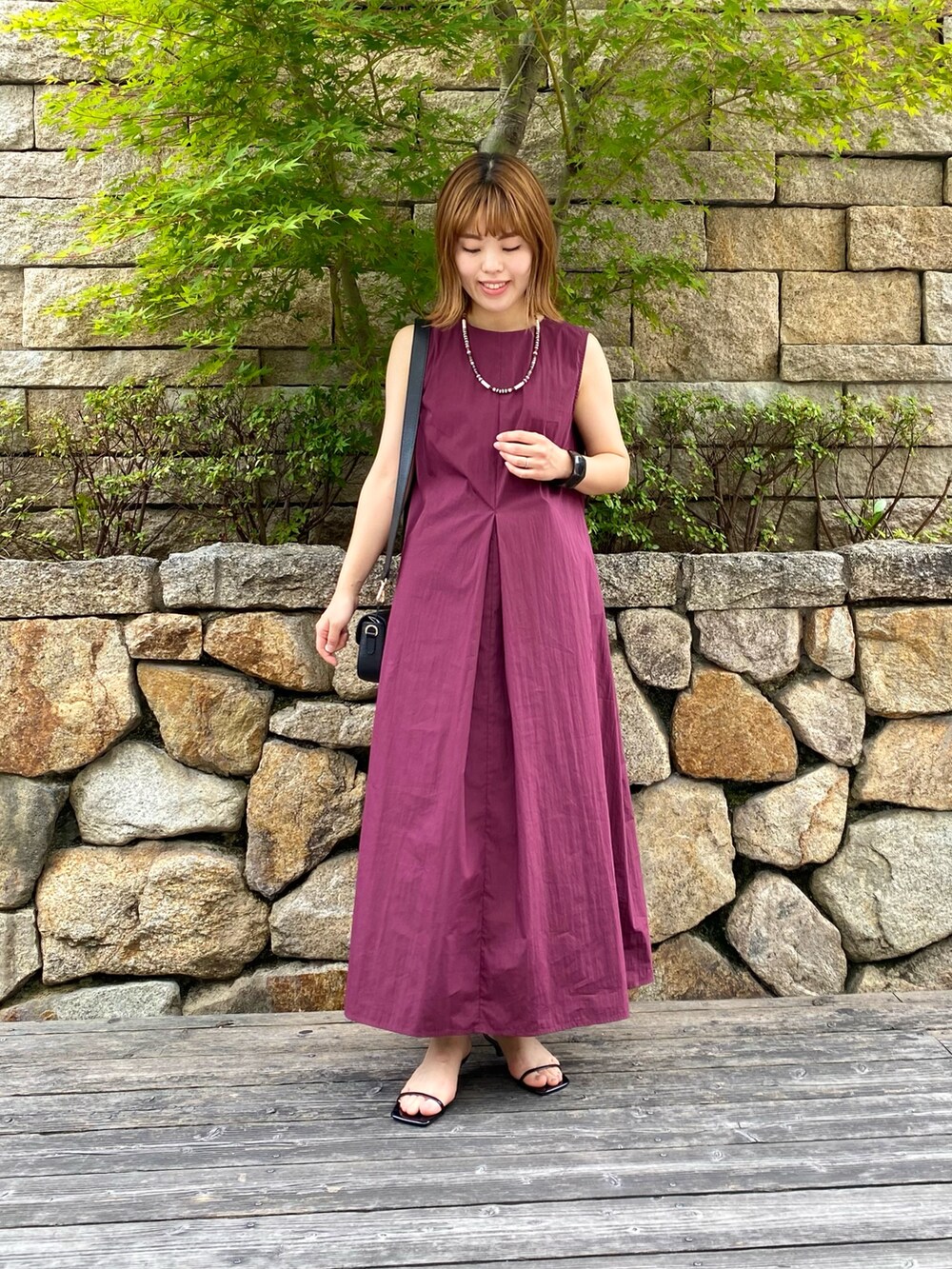 ブラック系のショルダーバッグ、ブラック系のサンダル、レッド系のワンピースを着用したレディースの夏コーディネートの2枚目の写真