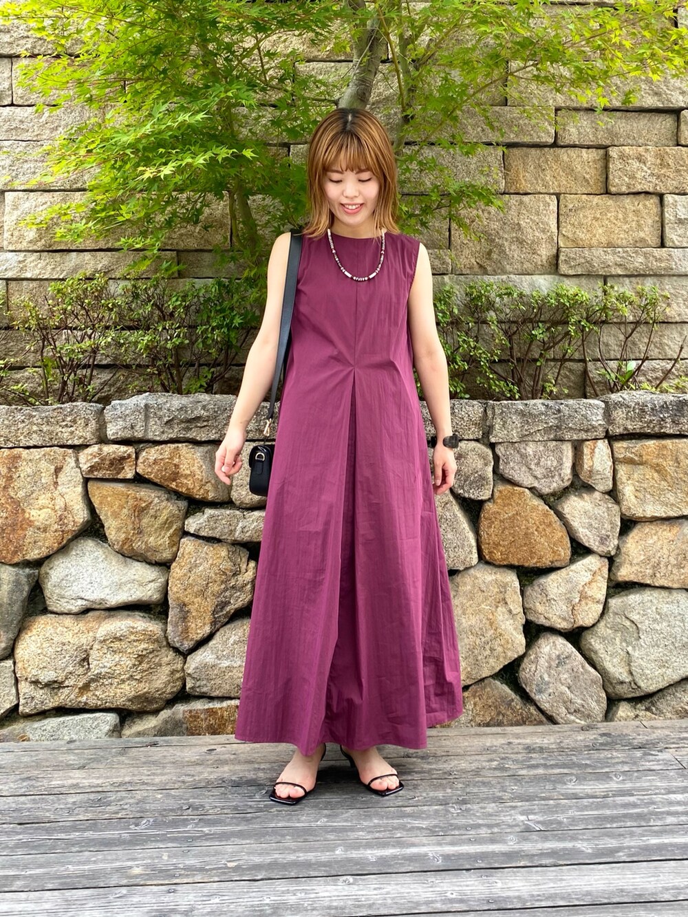 ブラック系のショルダーバッグ、ブラック系のサンダル、レッド系のワンピースを着用したレディースの夏コーディネートの3枚目の写真