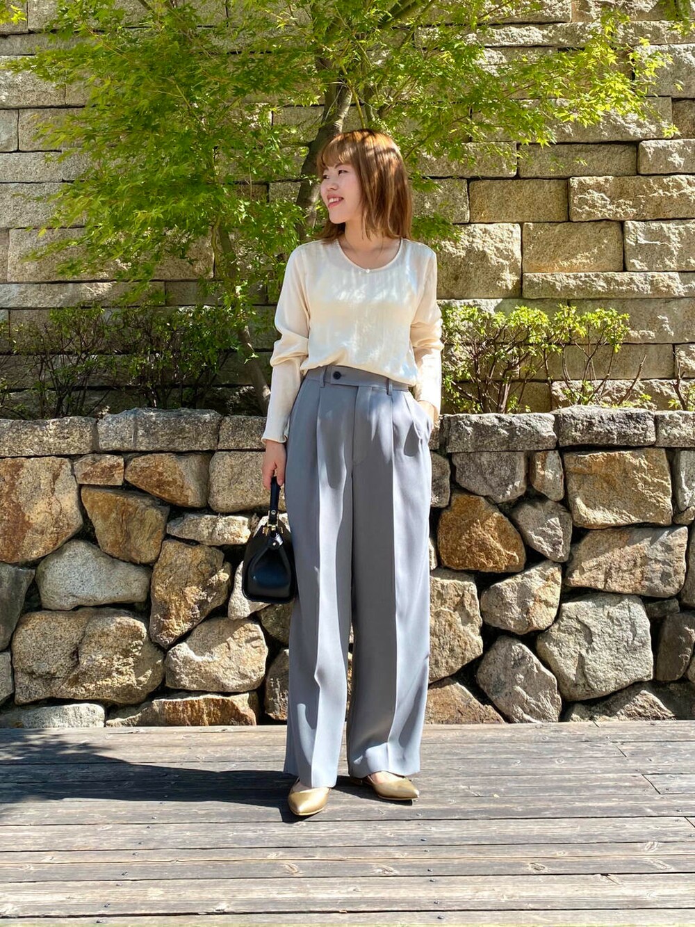 ブラック系のハンドバッグ、ゴールド系のパンプス、グレー系のその他パンツを着用したレディースの夏コーディネートの5枚目の写真