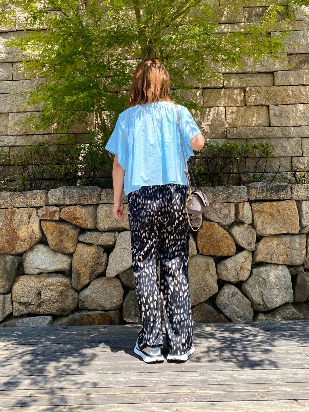 グレー系のショルダーバッグ、ホワイト系のスニーカー、ブルー系のシャツ/ブラウスを着用したレディースの夏コーディネートの4枚目の写真