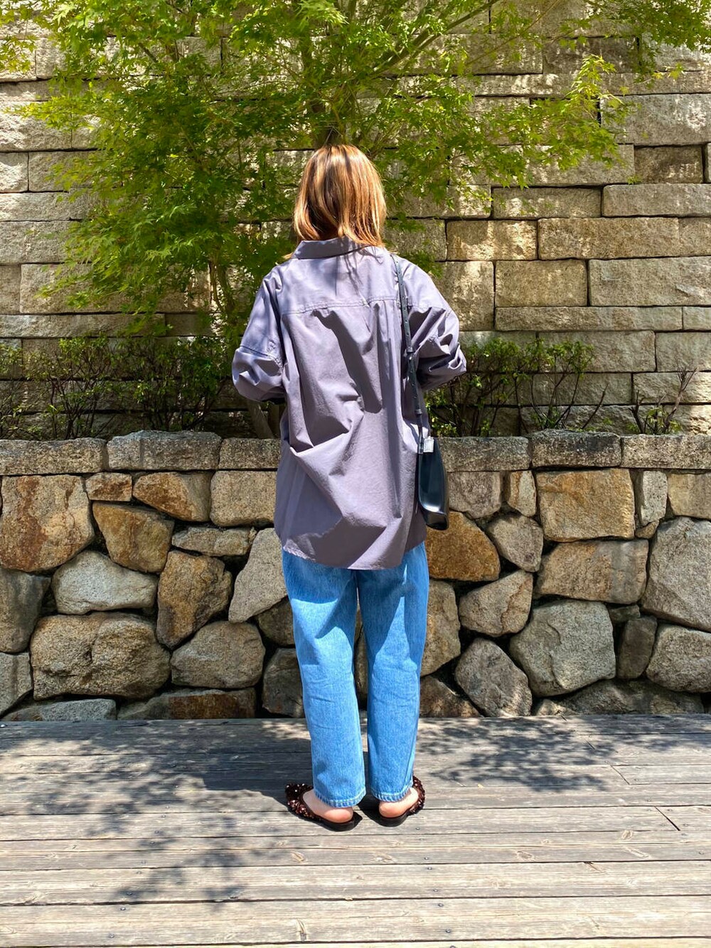 ブラック系のショルダーバッグ、ブルー系のデニムパンツ、ブラウン系のその他シューズを着用したレディースの夏コーディネートの5枚目の写真