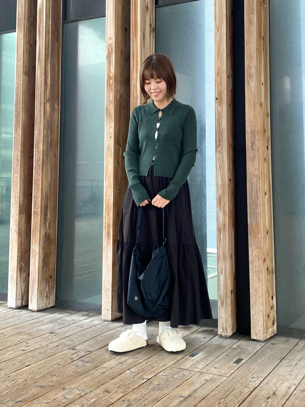 ブラック系のスカート、ホワイト系のサンダル、グリーン系のカーディガン/ボレロを着用したレディースの秋コーディネートの4枚目の写真