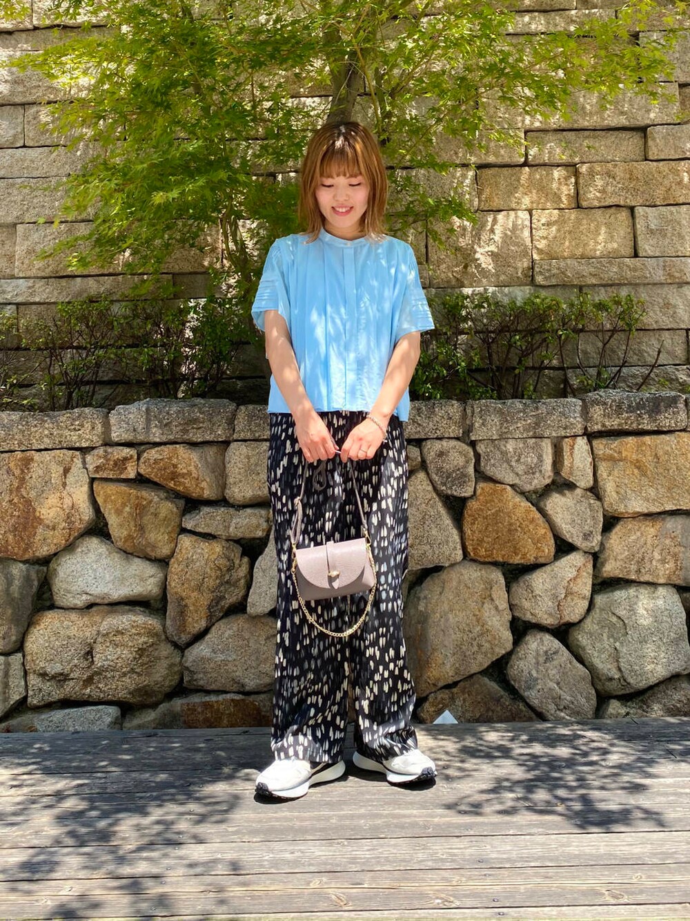 グレー系のショルダーバッグ、ホワイト系のスニーカー、ブルー系のシャツ/ブラウスを着用したレディースの夏コーディネートの5枚目の写真