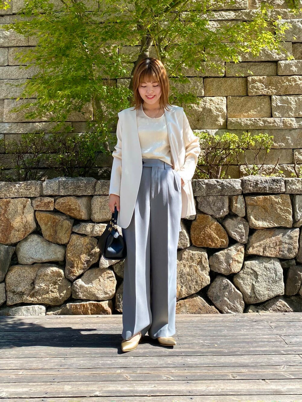 ブラック系のハンドバッグ、ゴールド系のパンプス、グレー系のその他パンツを着用したレディースの夏コーディネートの2枚目の写真