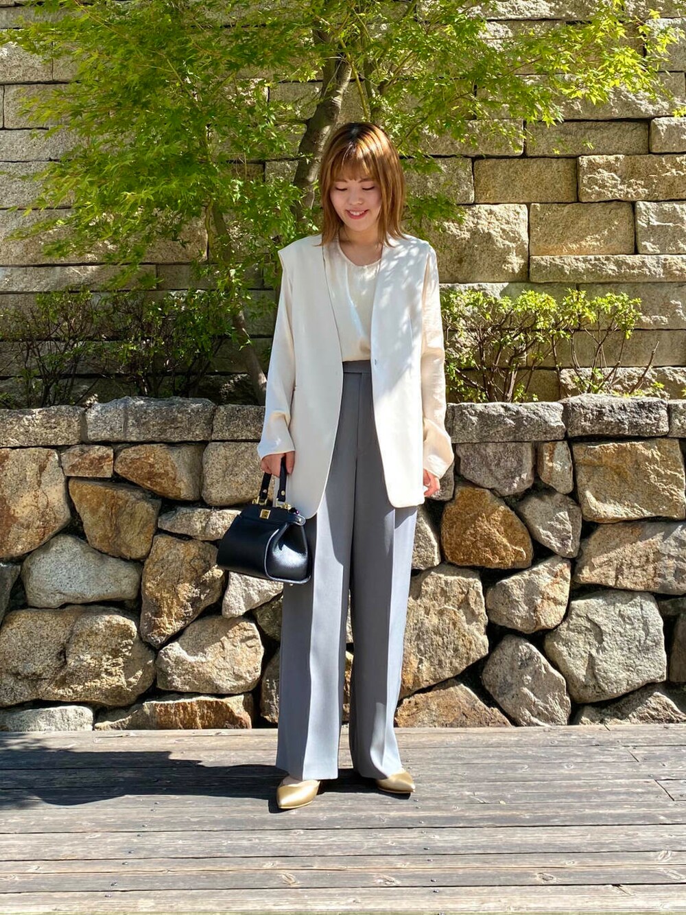 ブラック系のハンドバッグ、ゴールド系のパンプス、グレー系のその他パンツを着用したレディースの夏コーディネートの3枚目の写真