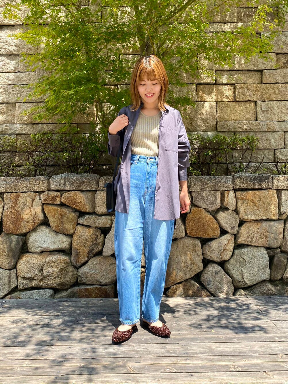 ブラック系のショルダーバッグ、ブルー系のデニムパンツ、ブラウン系のその他シューズを着用したレディースの夏コーディネートの2枚目の写真