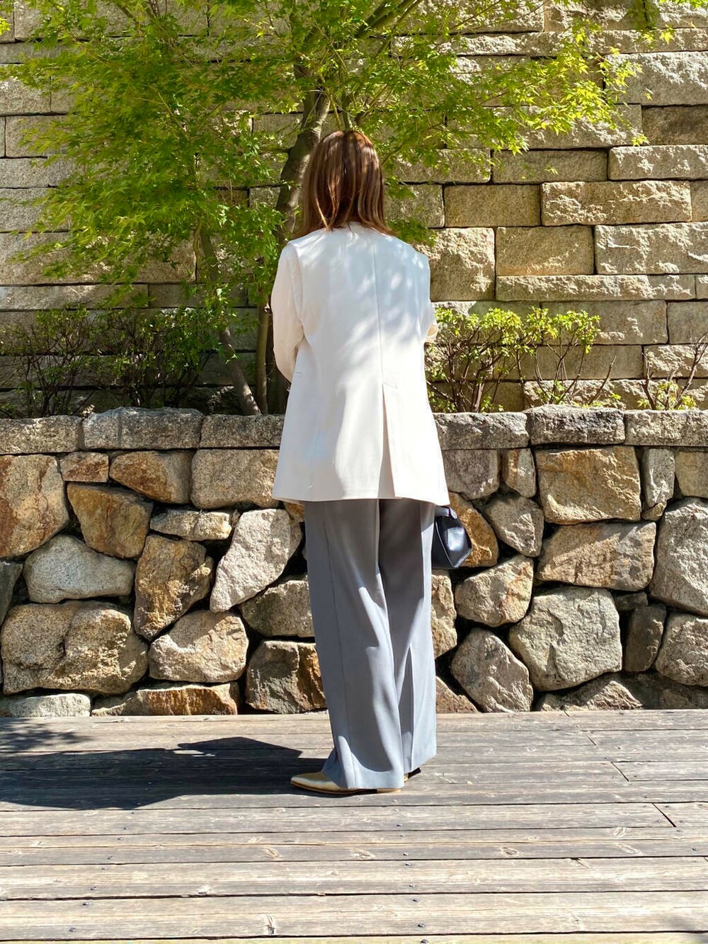 ブラック系のハンドバッグ、ゴールド系のパンプス、グレー系のその他パンツを着用したレディースの夏コーディネートの4枚目の写真