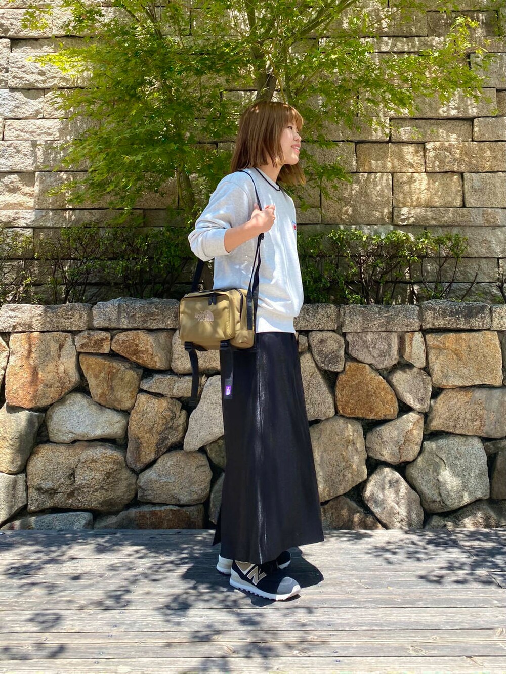 ブラック系のスカート、グレー系のスウェット、ブラック系のスニーカーを着用したレディースの夏コーディネートの3枚目の写真