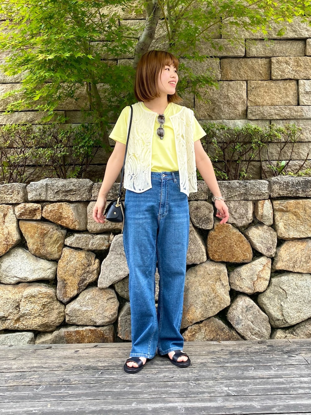 ブラック系のサンダル、ブラック系のショルダーバッグ、ホワイト系のシャツ/ブラウスを着用したレディースの夏コーディネートの2枚目の写真