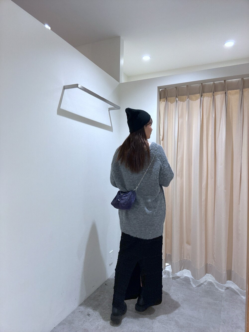 グレー系のカーディガン/ボレロ、ブラック系のスカート、シルバー系のハンドバッグを着用したレディースの秋コーディネートの2枚目の写真