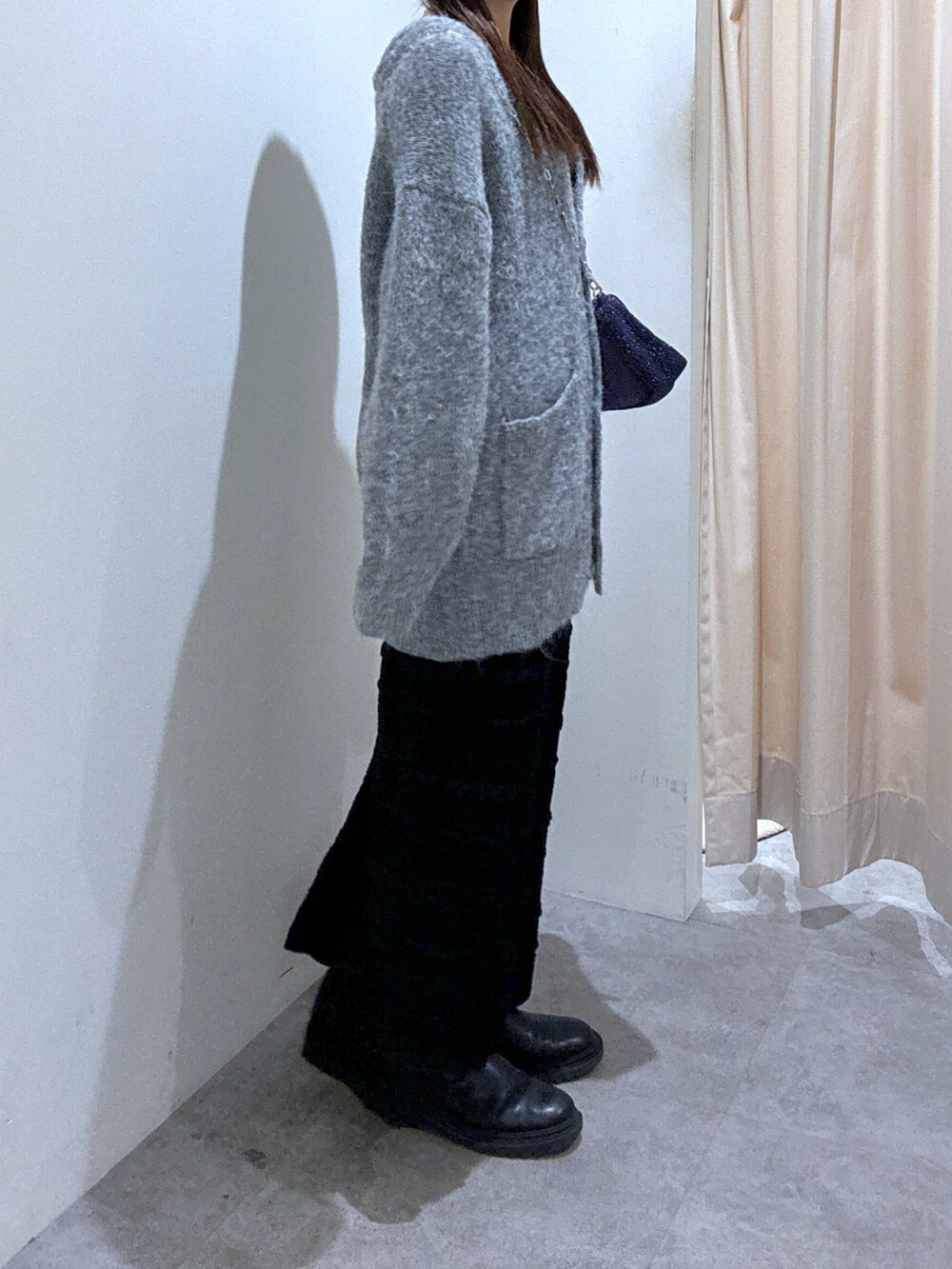 グレー系のカーディガン/ボレロ、ブラック系のスカート、シルバー系のハンドバッグを着用したレディースの秋コーディネートの4枚目の写真