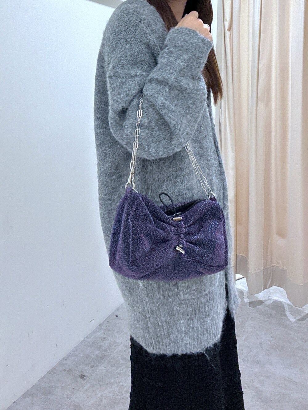 グレー系のカーディガン/ボレロ、ブラック系のスカート、シルバー系のハンドバッグを着用したレディースの秋コーディネートの3枚目の写真