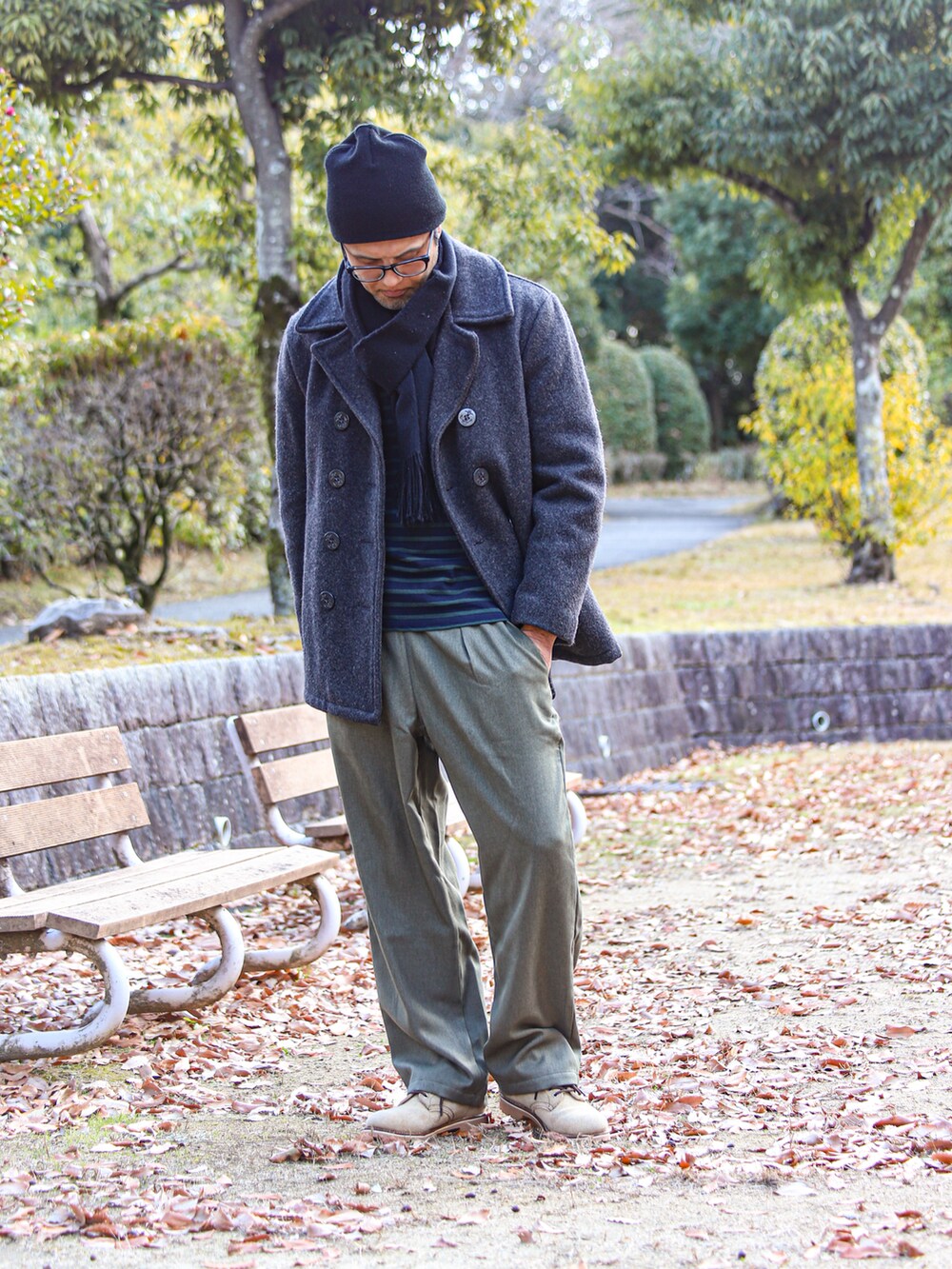 グレー系のピーコート、グリーン系のTシャツ/カットソー、グリーン系のパンツを着用したメンズの冬コーディネートの2枚目の写真