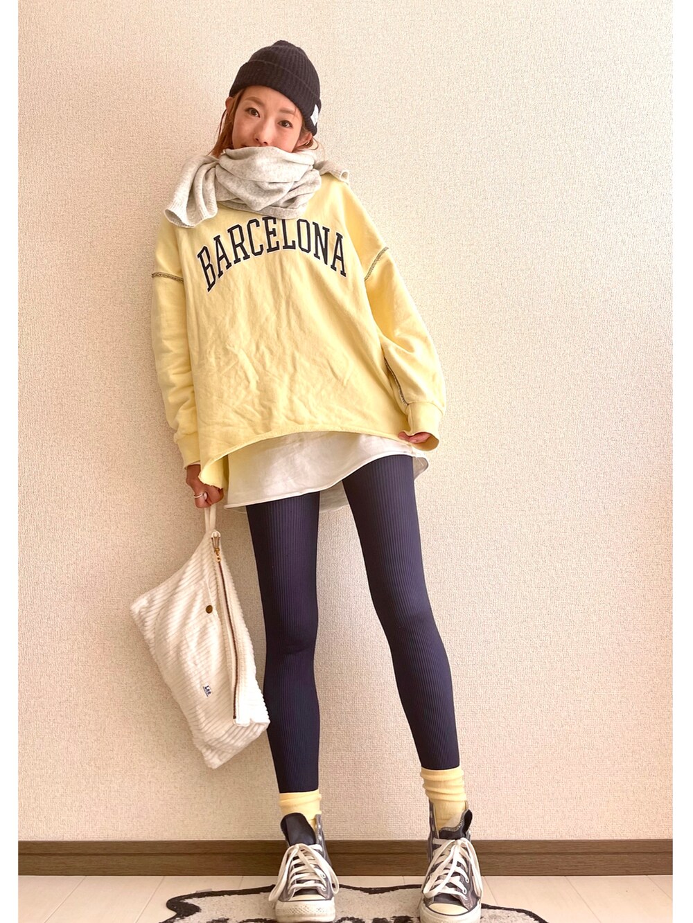 ホワイト系のクラッチバッグ、イエロー系のスウェット、ブルー系のスニーカーを着用したレディースの冬コーディネートの2枚目の写真