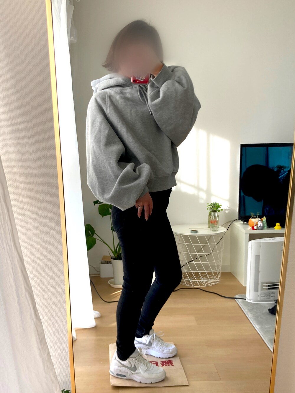 ブラック系のデニムパンツ、ホワイト系のスニーカー、グレー系のパーカーを着用したレディースの冬コーディネートの2枚目の写真