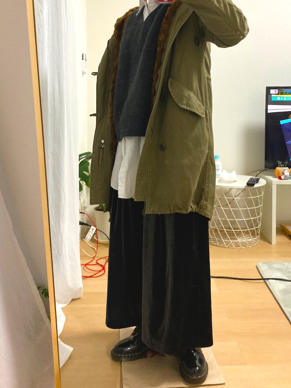 ブラック系のパンツ、ブラック系のブーツ、グリーン系のモッズコートを着用したレディースの冬コーディネートの2枚目の写真