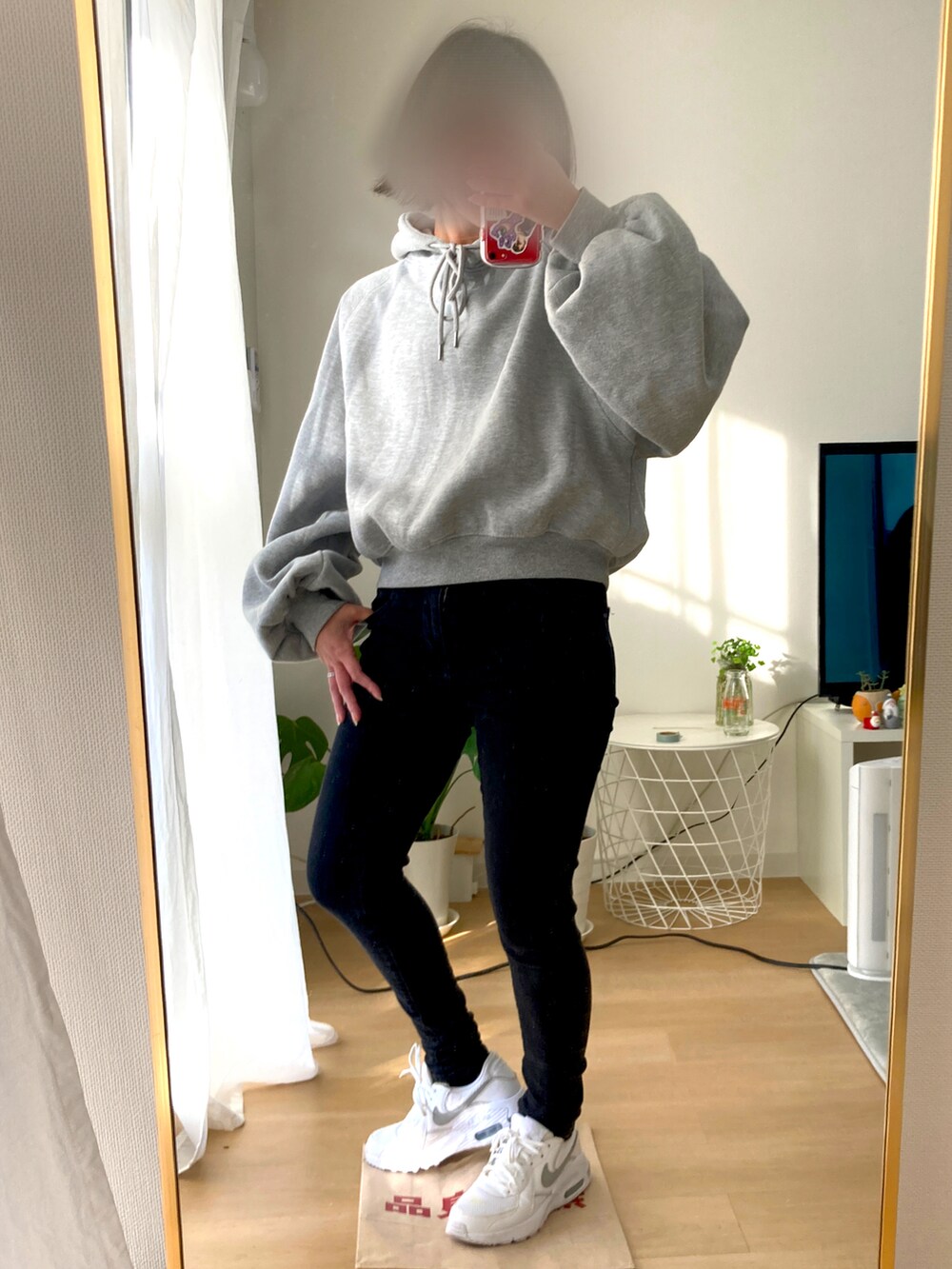 ブラック系のデニムパンツ、ホワイト系のスニーカー、グレー系のパーカーを着用したレディースの冬コーディネートの3枚目の写真