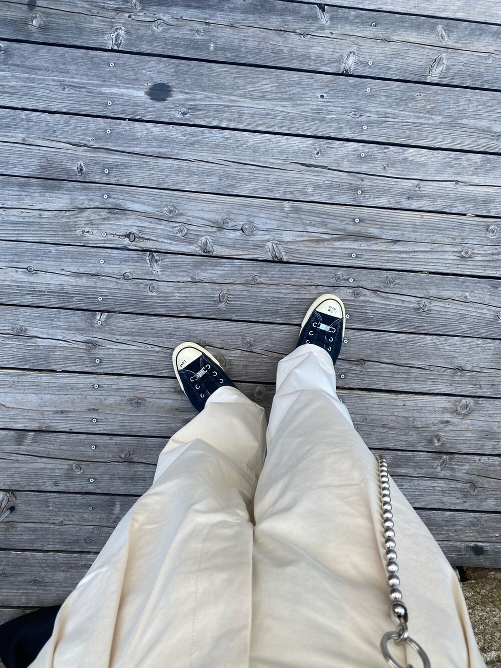 ブラック系のTシャツ/カットソー、ホワイト系のチノパンツ、ブラック系のスニーカーを着用したメンズの夏コーディネートの5枚目の写真