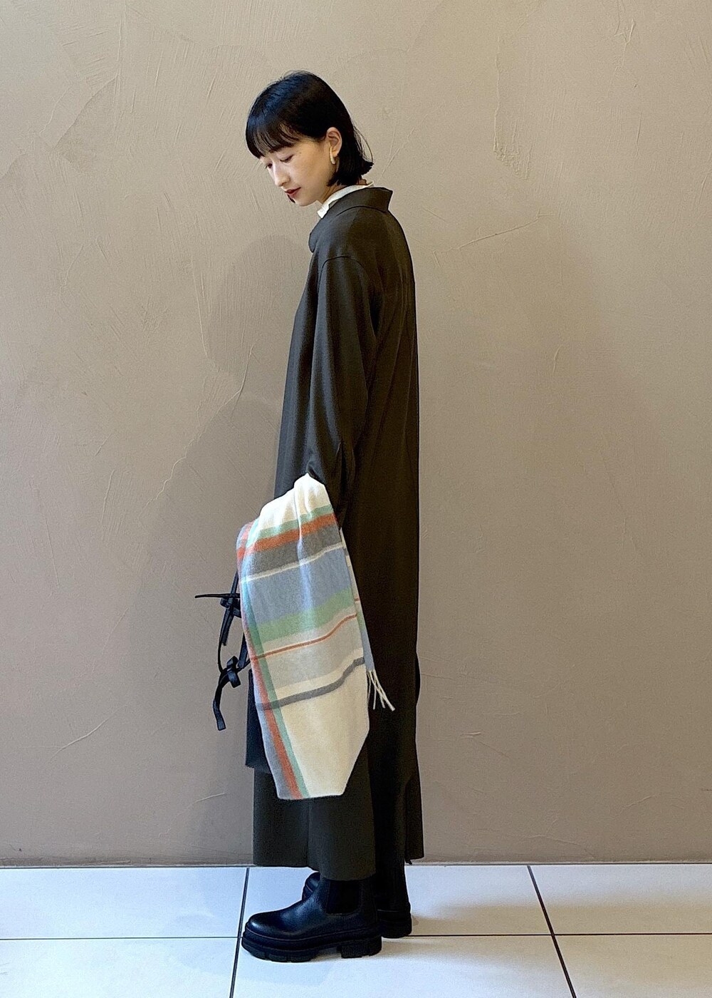 ブラック系のブーツ、グリーン系のワンピース、ホワイト系のニット/セーターを着用したレディースの冬コーディネートの2枚目の写真