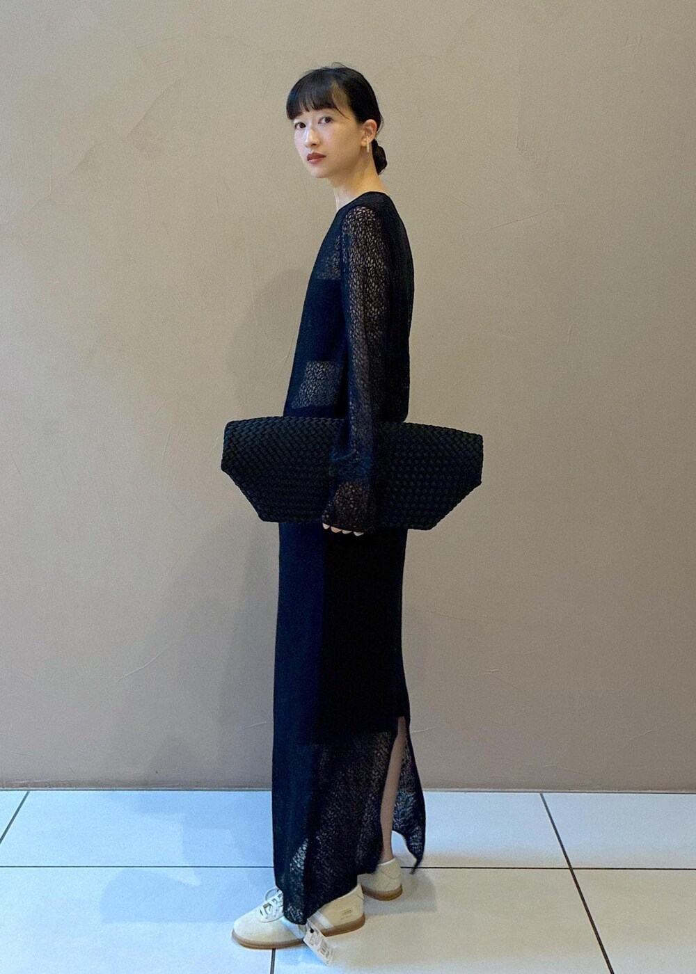 ブラック系のトートバッグ、ブラック系のワンピース、ホワイト系のスニーカーを着用したレディースの秋コーディネートの3枚目の写真