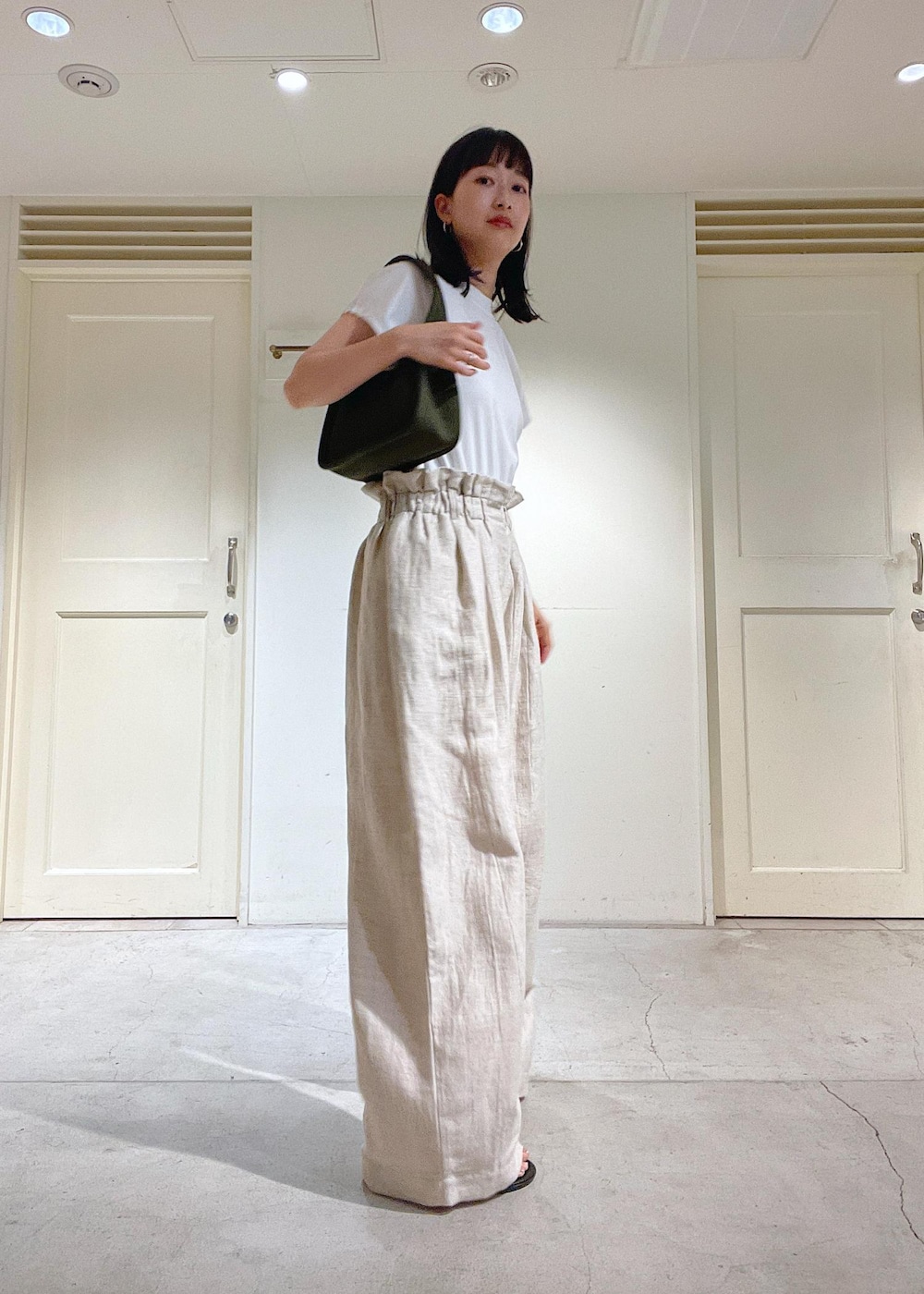 ブラック系のサンダル、グレー系のスラックス、ホワイト系のTシャツ/カットソーを着用したレディースの春コーディネートの3枚目の写真