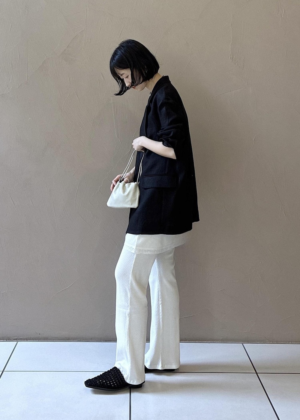 ブラック系のテーラードジャケット、ブラック系のサンダル、ホワイト系のキャミソールを着用したレディースの春コーディネートの3枚目の写真