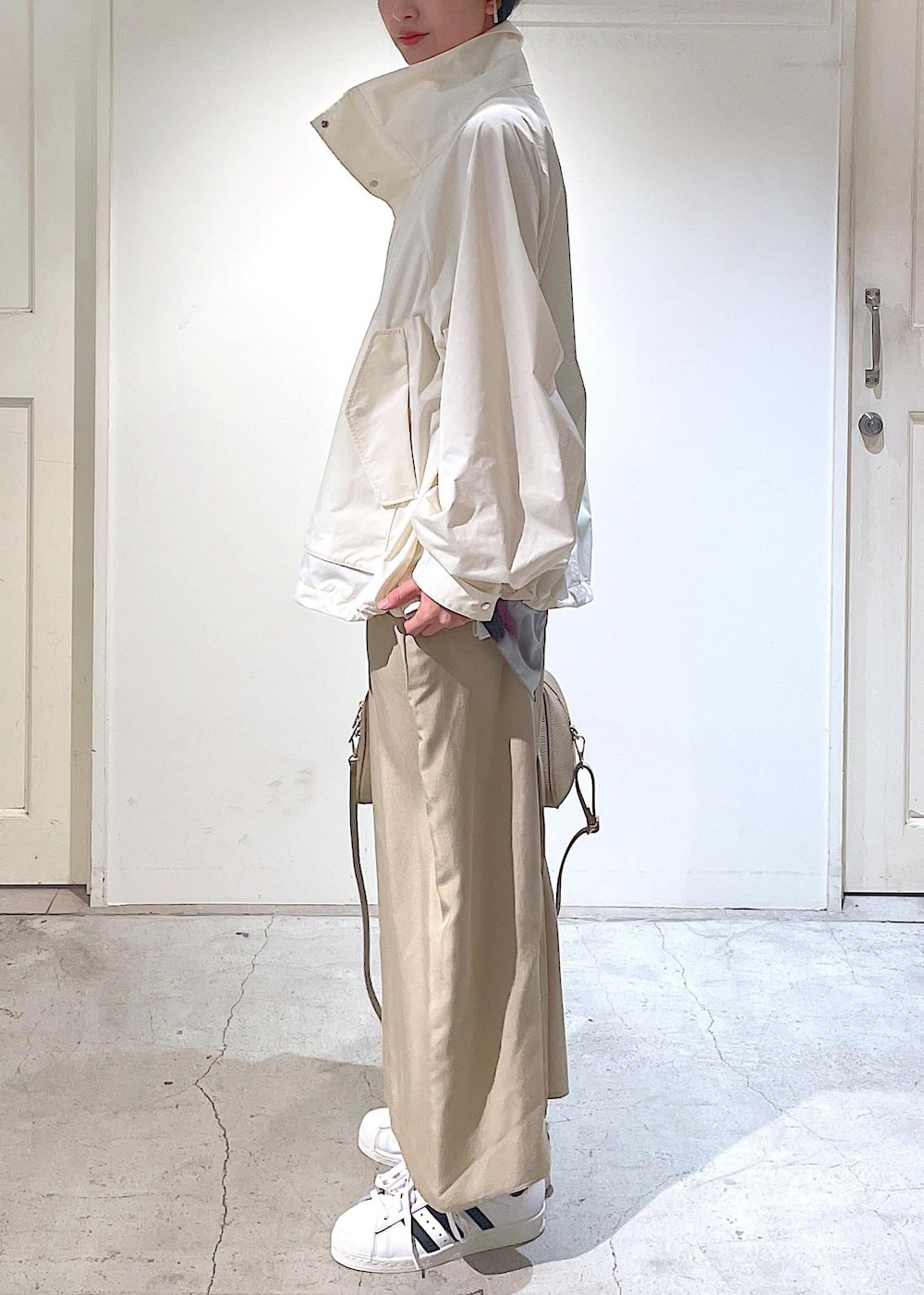 ベージュ系のワンピース、ホワイト系のブルゾン、ホワイト系のスニーカーを着用したレディースの冬コーディネートの6枚目の写真