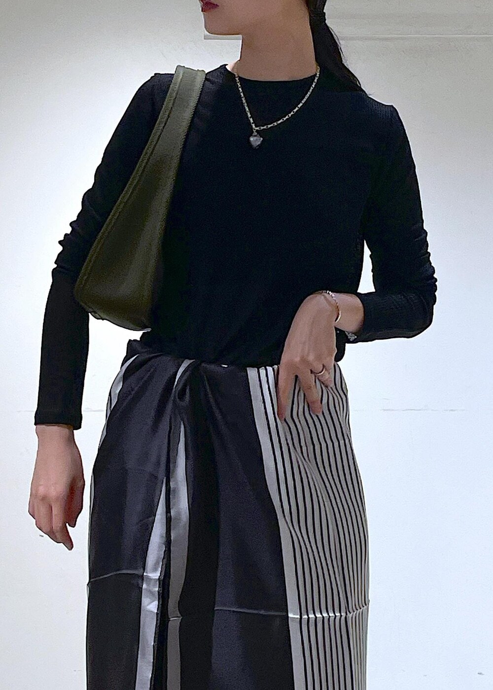 ブラック系のTシャツ/カットソー、グリーン系のハンドバッグ、ブラック系のブーツを着用したレディースの秋コーディネートの10枚目の写真