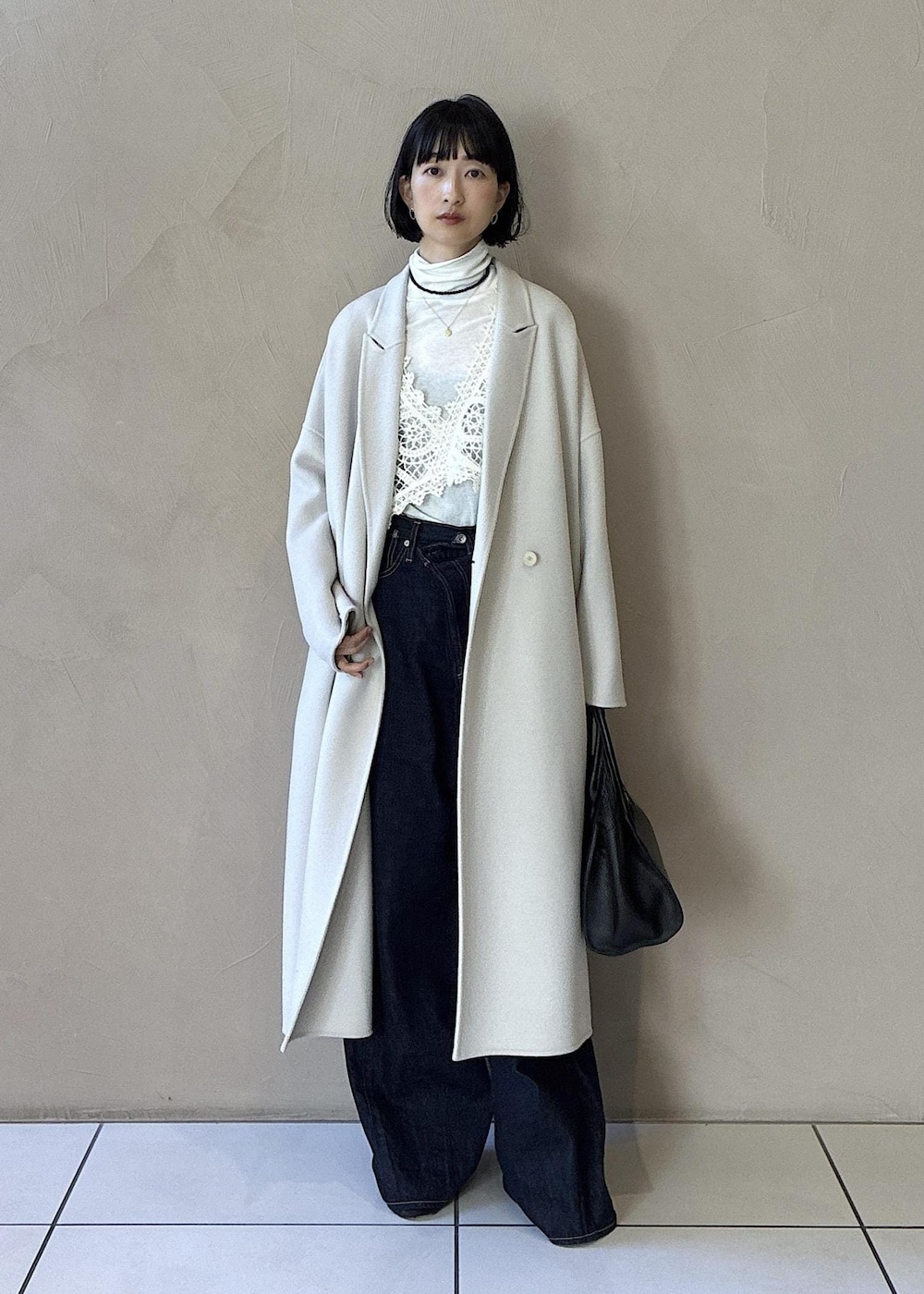ホワイト系のその他アウター、ホワイト系のチェスターコート、ブラック系のハンドバッグを着用したレディースの秋コーディネートの4枚目の写真