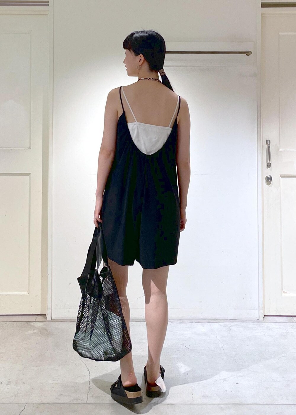 ブラック系のサンダル、ブラック系のトートバッグ、ブラック系のラッシュガードを着用したレディースの夏コーディネートの3枚目の写真