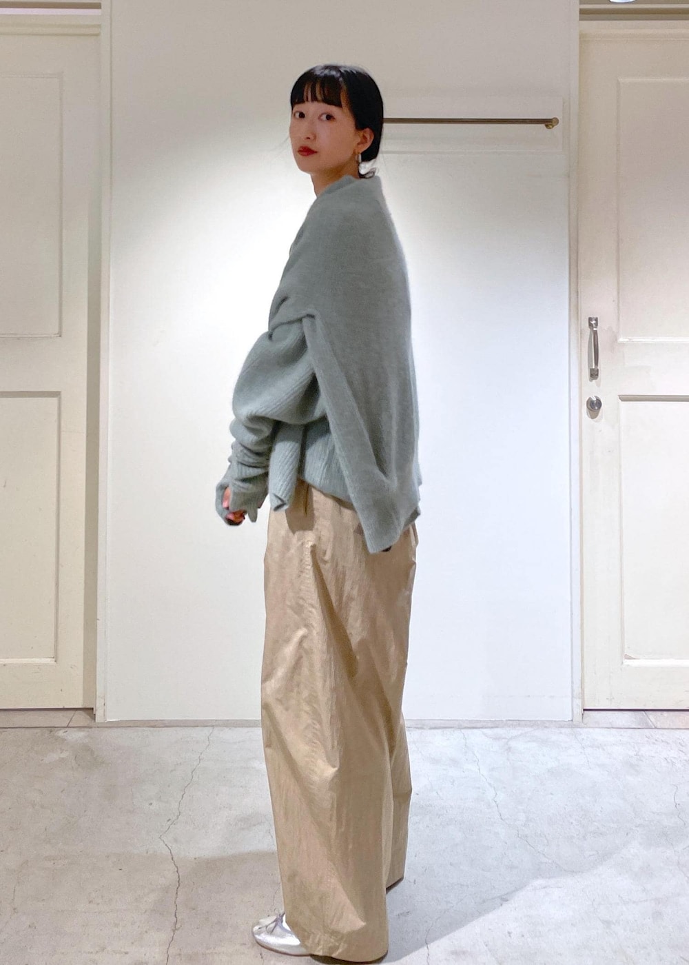 シルバー系のバレエシューズ、グレー系のショルダーバッグ、グリーン系のニット/セーターを着用したレディースの秋コーディネートの2枚目の写真