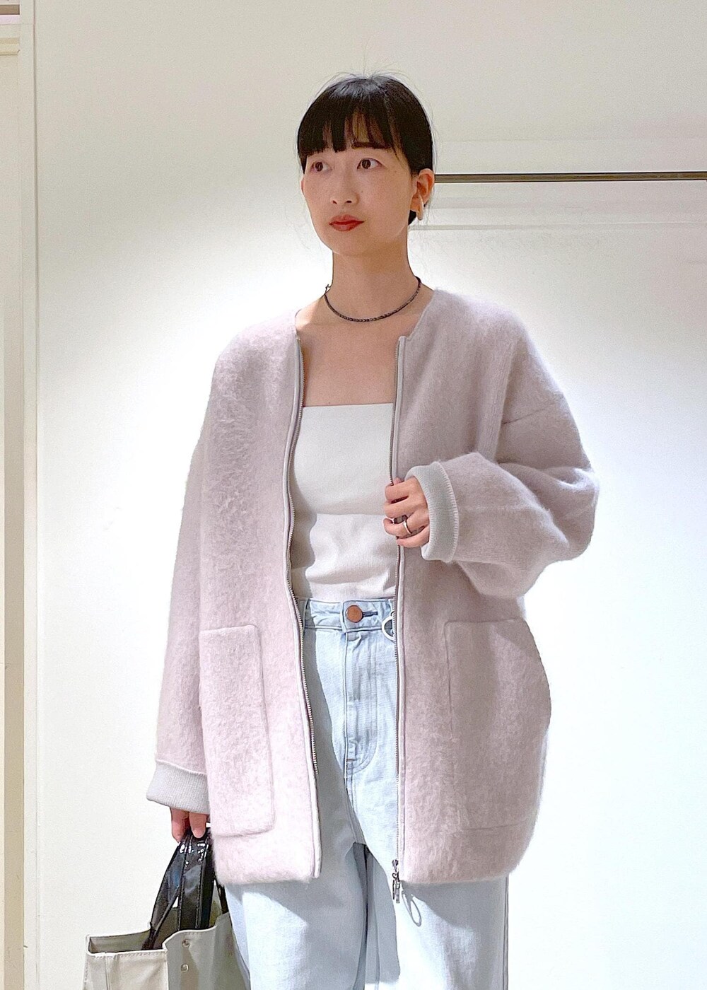 グレー系のトートバッグ、ホワイト系のチューブトップ、グレー系のブルゾンを着用したレディースの冬コーディネートの6枚目の写真