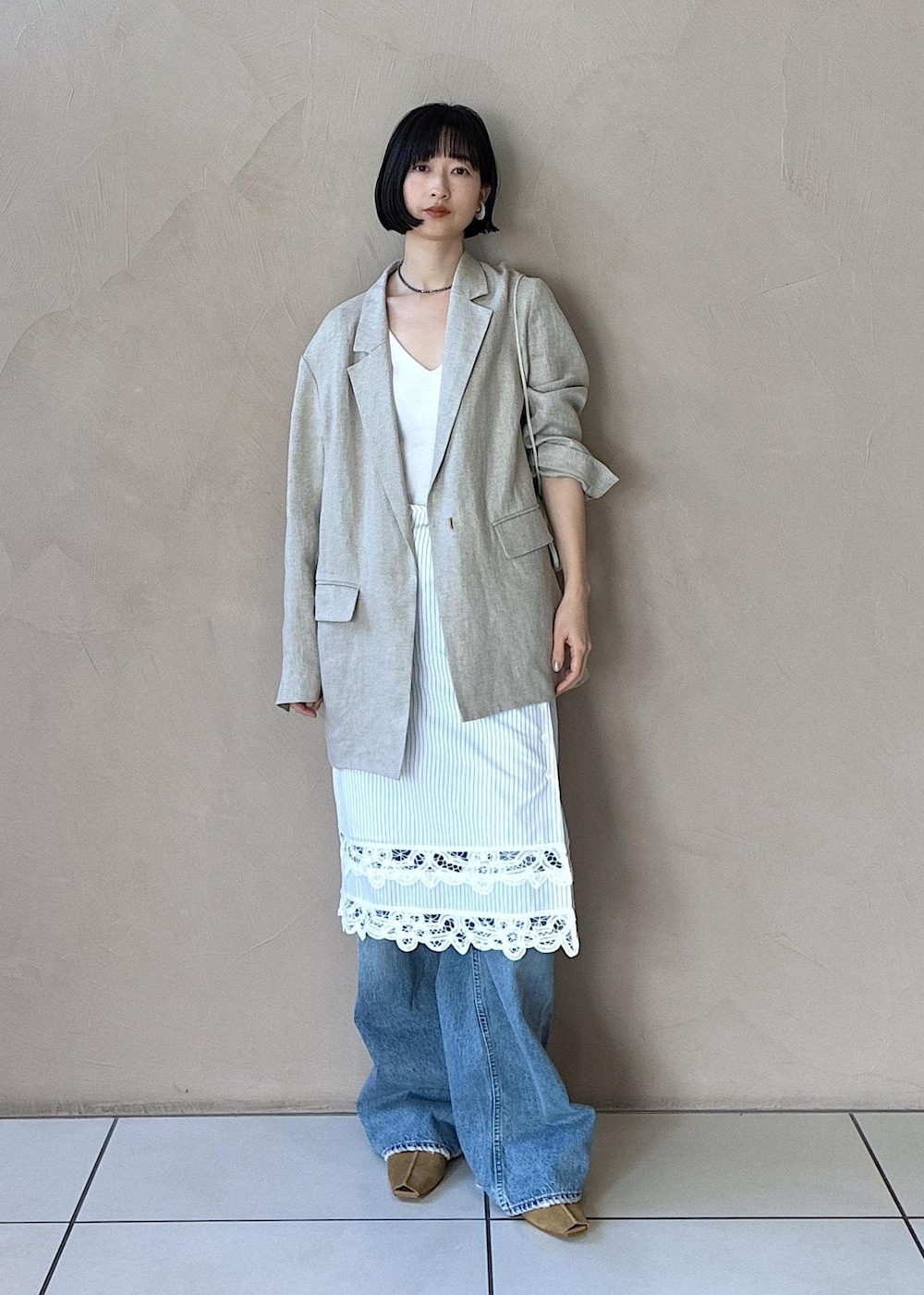 イエロー系のその他シューズ、ベージュ系のテーラードジャケット、ブルー系のデニムパンツを着用したレディースの冬コーディネートの3枚目の写真