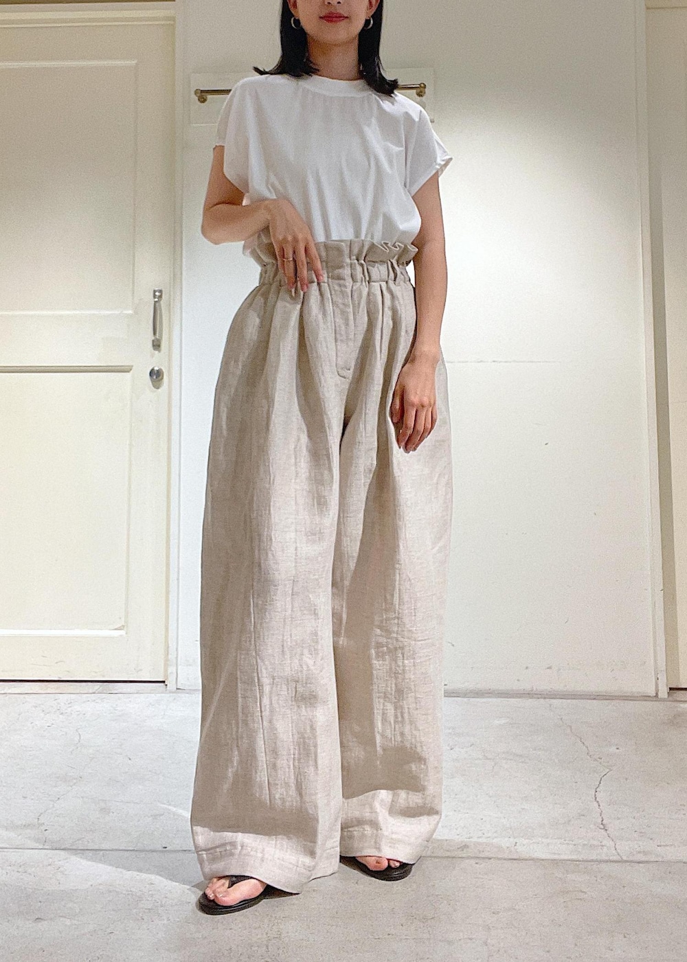 ブラック系のサンダル、グレー系のスラックス、ホワイト系のTシャツ/カットソーを着用したレディースの春コーディネートの4枚目の写真