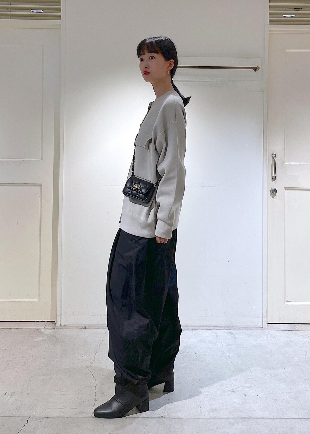 ブラック系のショルダーバッグ、ブラック系のカーゴパンツ、ブラック系のブーツを着用したレディースの秋コーディネートの2枚目の写真