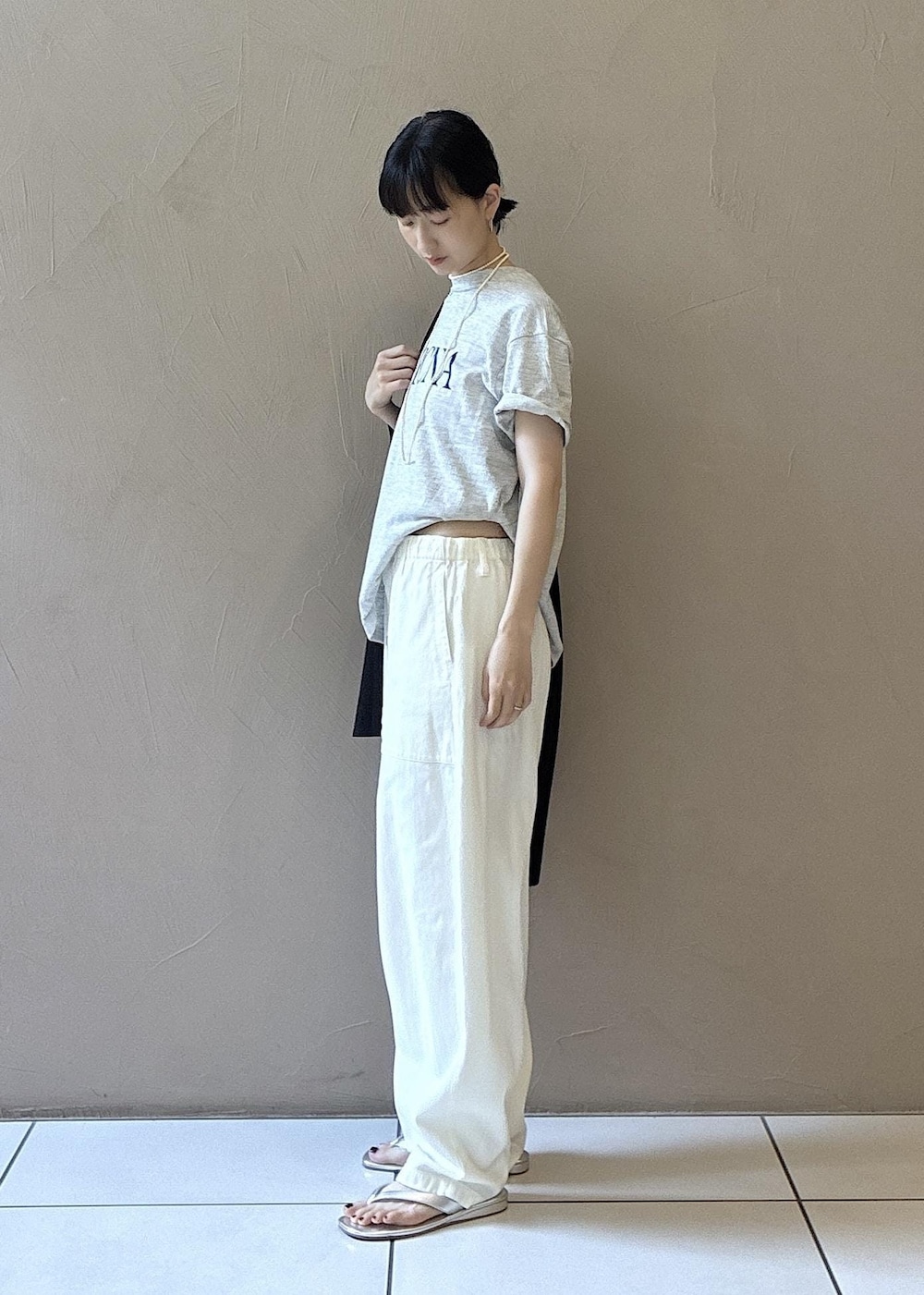 グレー系のTシャツ/カットソー、シルバー系のサンダル、ブラック系のテーラードジャケットを着用したレディースの夏コーディネートの2枚目の写真