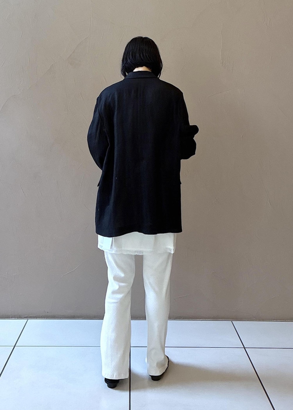 ブラック系のテーラードジャケット、ブラック系のサンダル、ホワイト系のキャミソールを着用したレディースの春コーディネートの7枚目の写真