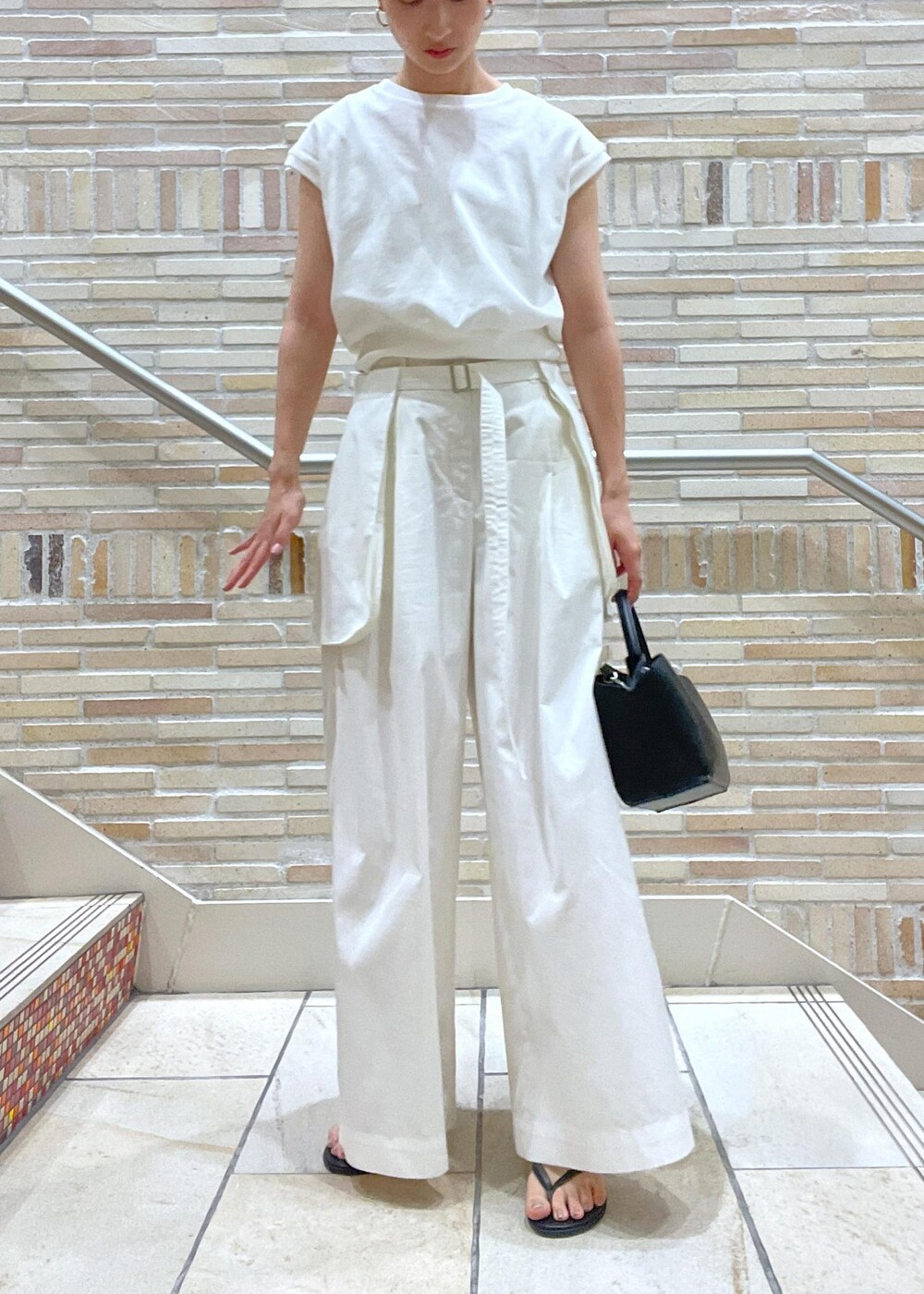 ホワイト系のTシャツ/カットソー、ホワイト系のその他パンツ、ブラック系のサンダルを着用したレディースの春コーディネートの6枚目の写真