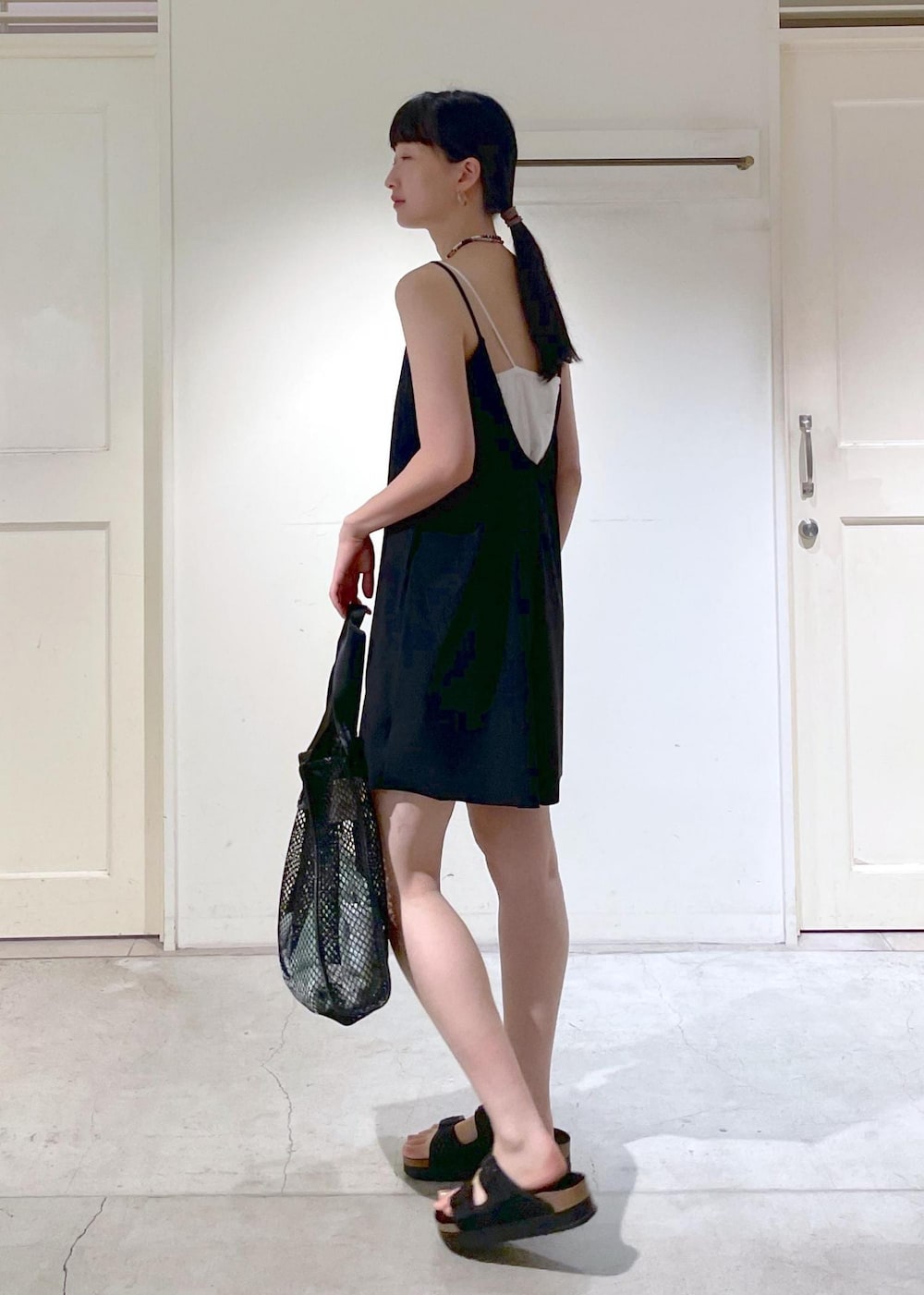 ブラック系のサンダル、ブラック系のトートバッグ、ブラック系のラッシュガードを着用したレディースの夏コーディネートの2枚目の写真