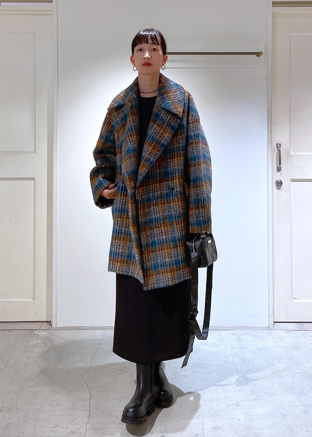 ブルー系のピーコート、ブラック系のブーツ、ブラック系のスカートを着用したレディースの秋コーディネートの5枚目の写真