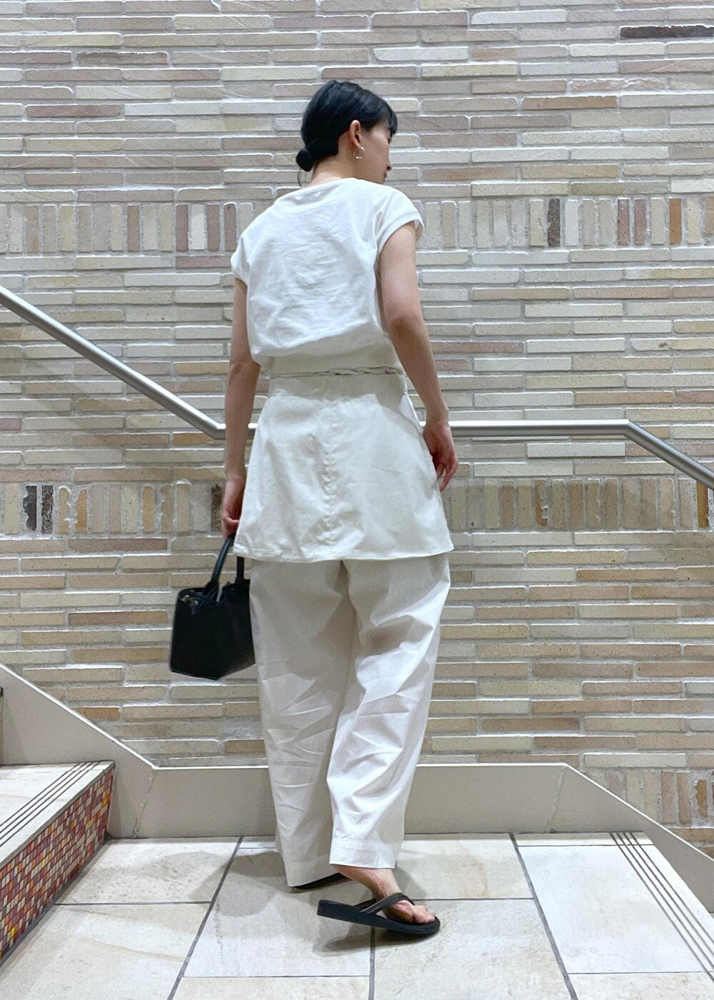 ホワイト系のTシャツ/カットソー、ホワイト系のその他パンツ、ブラック系のサンダルを着用したレディースの春コーディネートの4枚目の写真